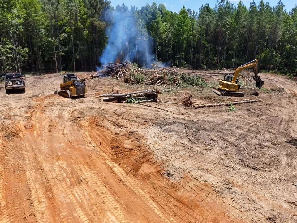 Heavy excavator and forestry mulcher clearing a commercial development site in Mississippi